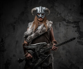 Naklejka premium Studio shot of scandinavian barbarian with guitar and horned helmet.