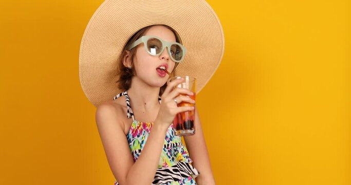 Child teenager girl in swimsuit and straw hat with lemonade metal straw in studio on yellow background, summer mood,