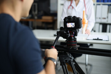 Videographer is filming doctor for online consultation and training - obrazy, fototapety, plakaty