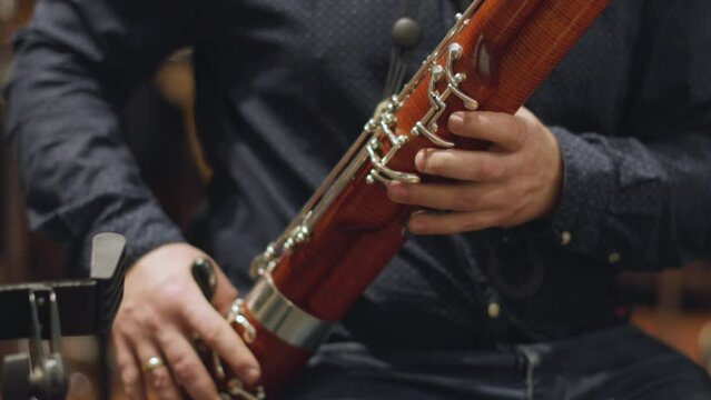 A slow motion video of a musician practicing the bassoon during a break in a chamber orchestra rehearsal
