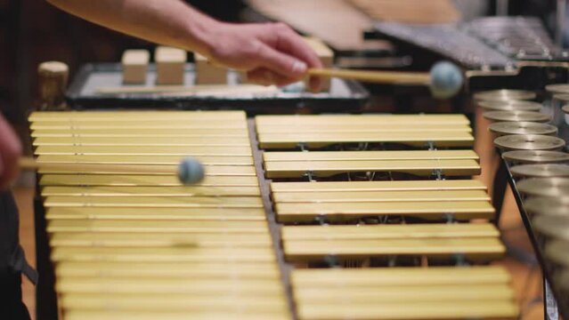 A slow motion video of a percussion player playing the vibrophone with mallets during an orchestra rehearsal