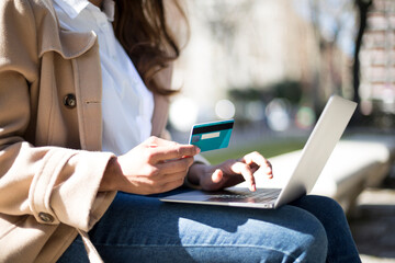 Unrecognizable woman using a card to shopping online outdoors