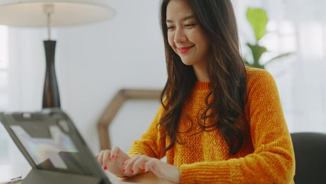 Young asian woman Working on table with computer tablet.asian female happy about good email news,passed exam,got a job,new opportunity,working online at home.woman using tablet remote working at home