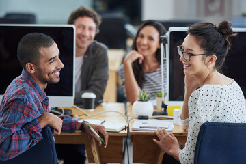 They share a great working relationship. a group of smiling designers sitting at their workstations in an office.