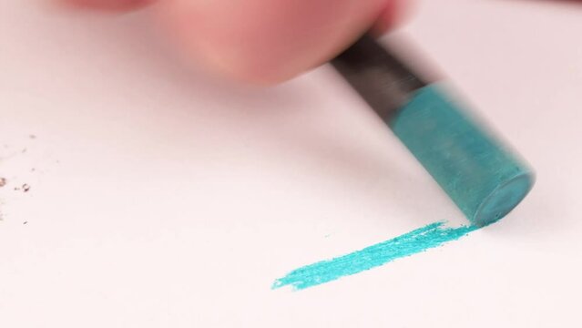 Drawing with a light blue crayon on a piece of paper.