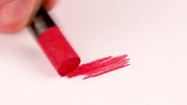 Drawing with a red crayon on a piece of paper.