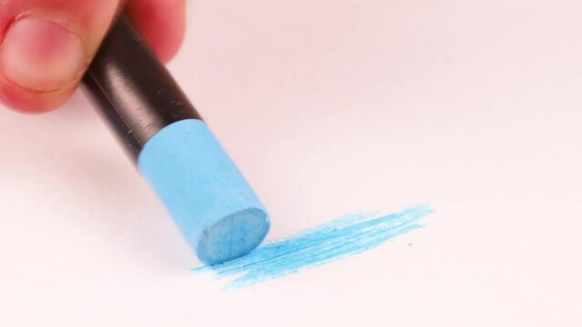 Drawing with a very light blue crayon on a piece of paper.