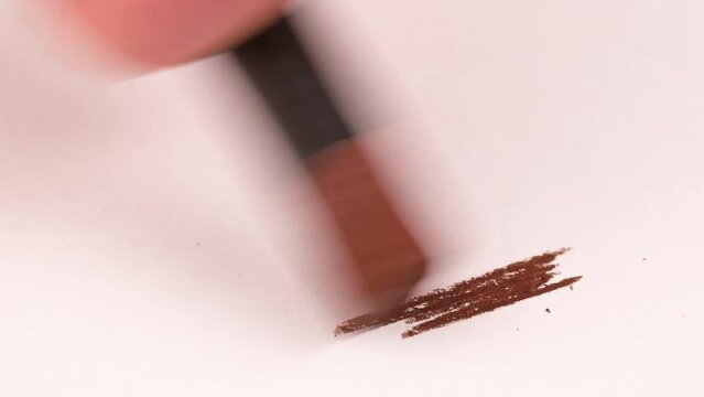 Drawing with a brown crayon on a piece of paper.