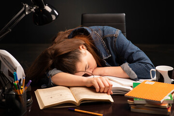 Female student sleeping with books at her desk.