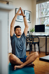 Athletic man doing breathing exercise while practicing Yoga at home.