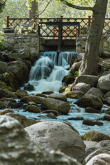 Waterfall cascade in Olivia public park Gdansk Poland. River waterfall falls from cliff and trees. Tourist attraction with small waterfall and clear water Long exposure Unity with nature