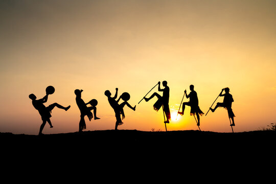 Silhouettes of Ede boys and girls performing their traditional dance during sunset in Pleiku town, Gia Lai province, Vietnam.