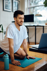 Fototapeta premium Happy athlete stretching during online exercise class at home.