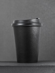 Takeaway coffee cup on black table and dark background.