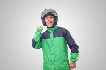 Portrait of Asian online taxi driver wearing green jacket and helmet showing good job sign, thumb...