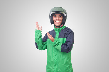 Portrait of Asian online taxi driver wearing green jacket and helmet pointing at empty space with finger. Isolated image on white background