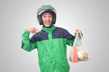 Portrait of Asian online taxi driver wearing green jacket and helmet delivering the vegetables from traditional market. Isolated image on white background