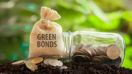 Money bag with the words GREEN BONDS with coins and a glass jar investment in bond concept Raising funds to fund environmentally friendly projects green bond