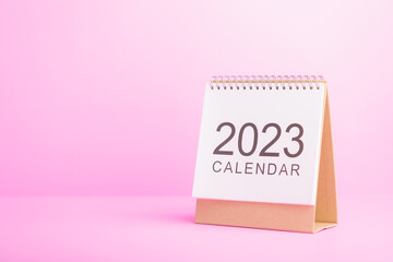 First page of white new 2023 desk calendar on pink background. 2023 Planning and scheduling concept.