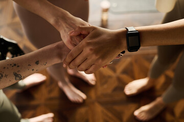 Close-up of friends holding hands while exercising in team during sport training