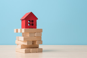 Red house model on wooden blocks. Uncertainty and risk in real estate market. Mortgage financial concept - 581712087