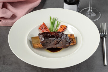 Long cooked marinated beef ribs on a white porcelain plate