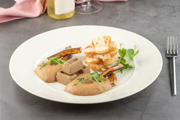 Foie gras with sauce and crispy bread on a white porcelain plate
