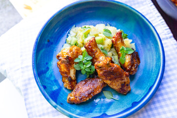 Chicken wings Hähnchenschenkel gebraten mit Kartoffelsalat in einem schönen Teller angerichtet von oben fotografiert 