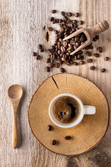 Top view of cup of Italian espresso with roasted coffee beans on rough wooden background.