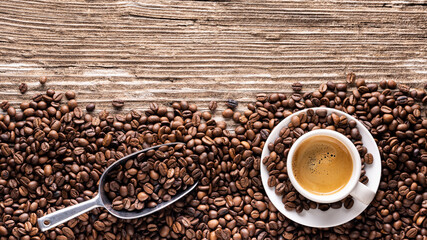 Fototapeta premium Panoramic top view of Italian espresso cup with roasted coffee beans on rough wooden background. Empty space