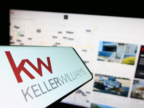 Stuttgart, Germany - 03-13-2023: Smartphone with logo of real estate company Keller Williams Realty Inc. on screen in front of website. Focus on center-left of phone display.