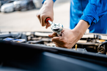 Close up of view Auto mechanic repairman using a socket wrench working engine repair in the garage, changing spare parts, checking the mileage of the car, checking and maintenance service concept.