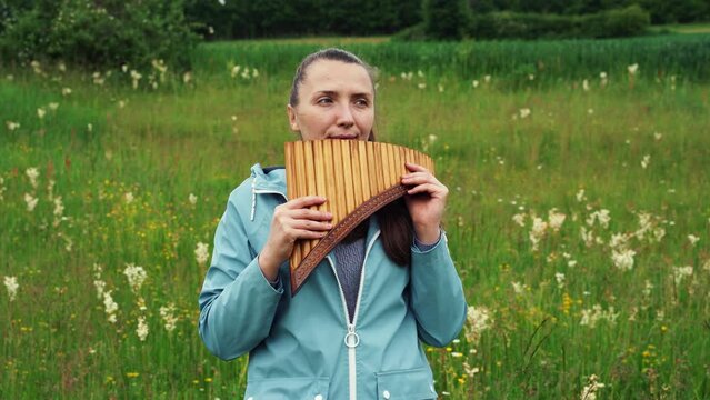 A young woman plays the pan flute in nature