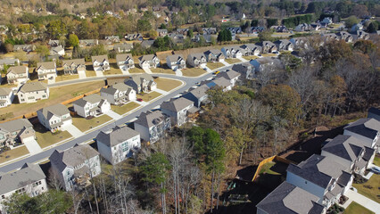 Urban sprawl master planned community with row of detached single family houses, trees and...