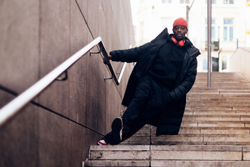 Hypebeast culture - young African American man with attitude walking down public city stairs -...