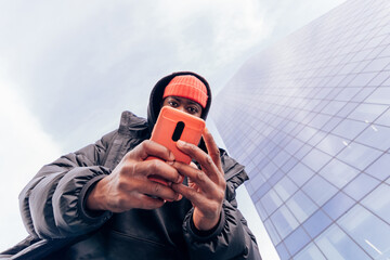 African American street style hypebeast influencer is captured recording a post on his cell phone...