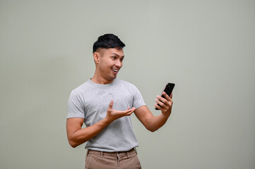 Happy Asian man looks at his phone screen, surprising with an online sale promotion