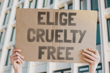 The phrase " Elige cruelty free " is on a banner in men's hands. Animal rights protest. Protection. City. Urban. Rally. Freedom. Stop animal testing. Equality. Justice. Care. Life. Humanity