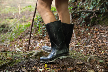 Photographie de bottes dans la forêt. Une personne fait une pause avec son bâton de marche.