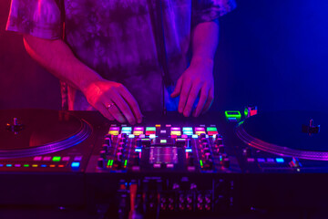 Close up of DJ hands on dj console mixer during concert in the club