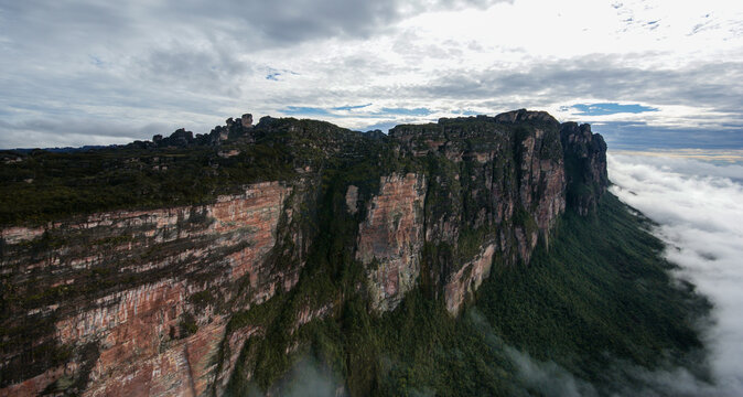 Towering sandstone rock cliffs of Auyan Tepui in the morning light with clouds on the lower slopes, Venezuela