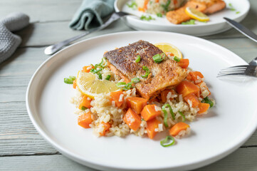 Fried salmon with skin served with brown rice and vegetables on a plate