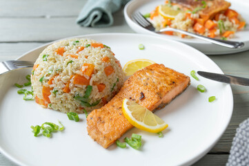 Fried salmon with brown rice, peas, carrots and leek on a plate