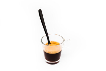 imagen de una taza de cristal con café y su espuma con una cuchara negra 
