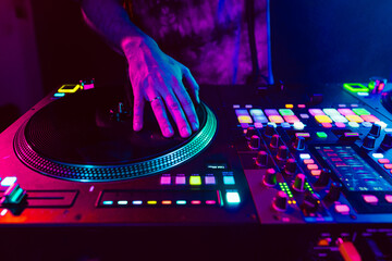 Close up of DJ hands on dj console mixer during concert in the club