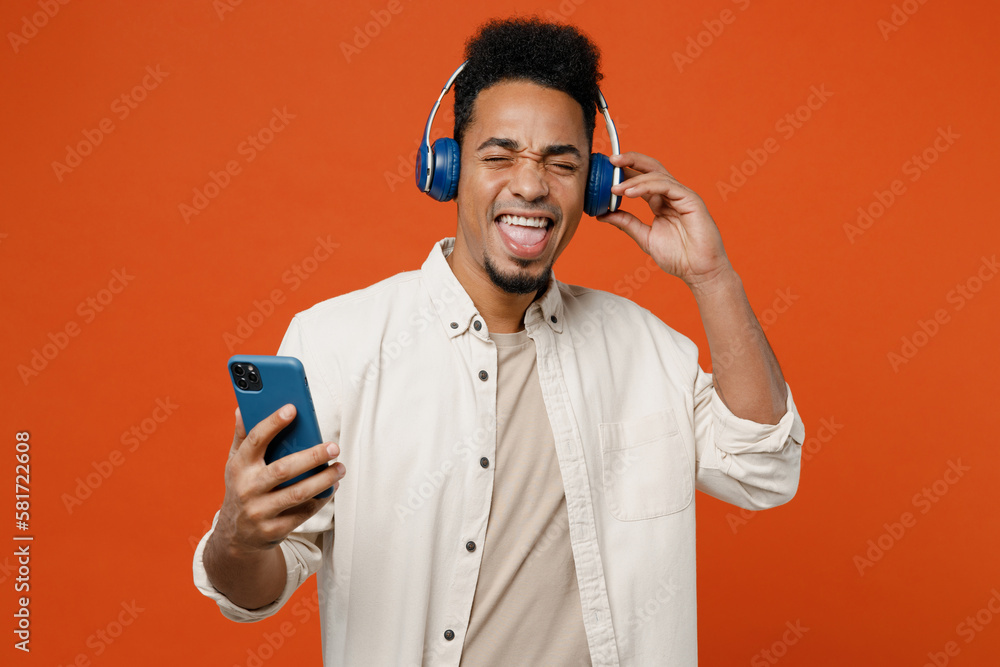 Wall mural young excited man of african american ethnicity wear light shirt casual clothes headphones listen to