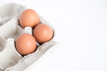 Detail of an open recycled cardboard egg carton with some eggs inside on a white background with copy space.