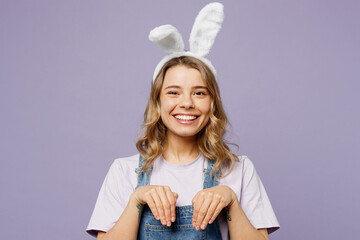 Young happy cmiling cheerful woman wearing casual clothes bunny ears hold hand pov rabbit look camera isolated on plain pastel light purple background studio portrait. Lifestyle Happy Easter concept.