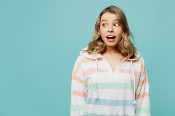 Fototapeta premium Young caucasian surprised shocked excited fun, cool blonde woman wear hoody look aside on workspace area mock up isolated on plain pastel light blue cyan background studio portrait. Lifestyle concept.