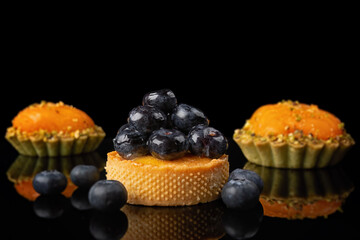 Desserts with blueberries, peaches and mangoes on a black background